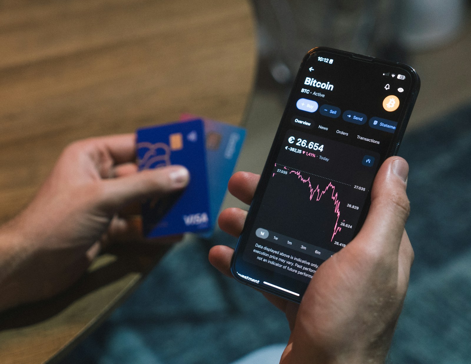 Smartphone mit Banking App und Laptop mit Dashboard auf einem Schreibtisch