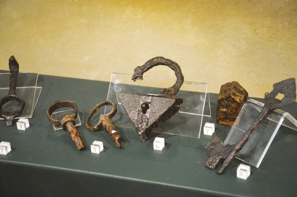 Ein Vorhängeschloss mit zwei Schlüsseln liegt auf einer grauen Metallfläche