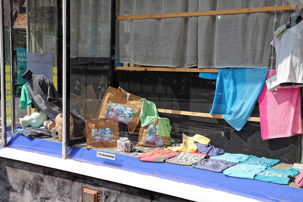 Beleuchtetes Schaufenster mit ausgestellten Waren und einem gläsernen Eingang an einer Straße