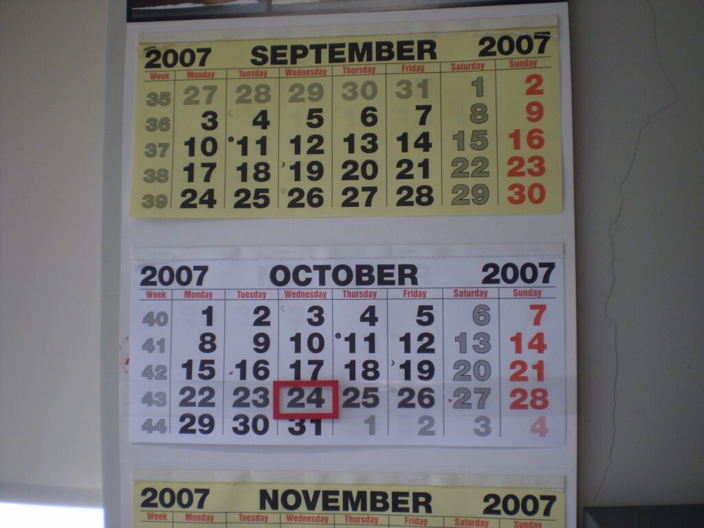 Aufgeschlagener Wandkalender mit markierten Wochen und einem Filzstift an der Seite