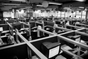 Ein Telefonheadset liegt neben Tastatur und Notizblock auf einem Arbeitsplatz im Büro