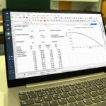 Laptop auf einem Schreibtisch mit einer geöffneten Tabellenkalkulation und Zahlenspalten