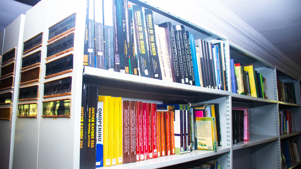 Reihe gebundener Gesetzbücher mit beschrifteten Rücken in einem dunklen Holzregal