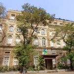 Die steinerne Fassade eines Bankgebäudes mit hohen Fenstern und schwerem Eingangsportal