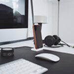 Ein Headset liegt neben einer Tastatur und einem Notizblock auf einem hellen Schreibtisch