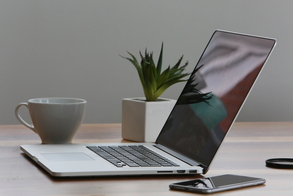 Eine Tasse Kaffee steht neben einem ge&ouml;ffneten Laptop auf einem Schreibtisch