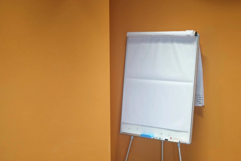 Ein Flipchart mit beschriebenem Papier und mehrere Filzstifte auf einer Ablage